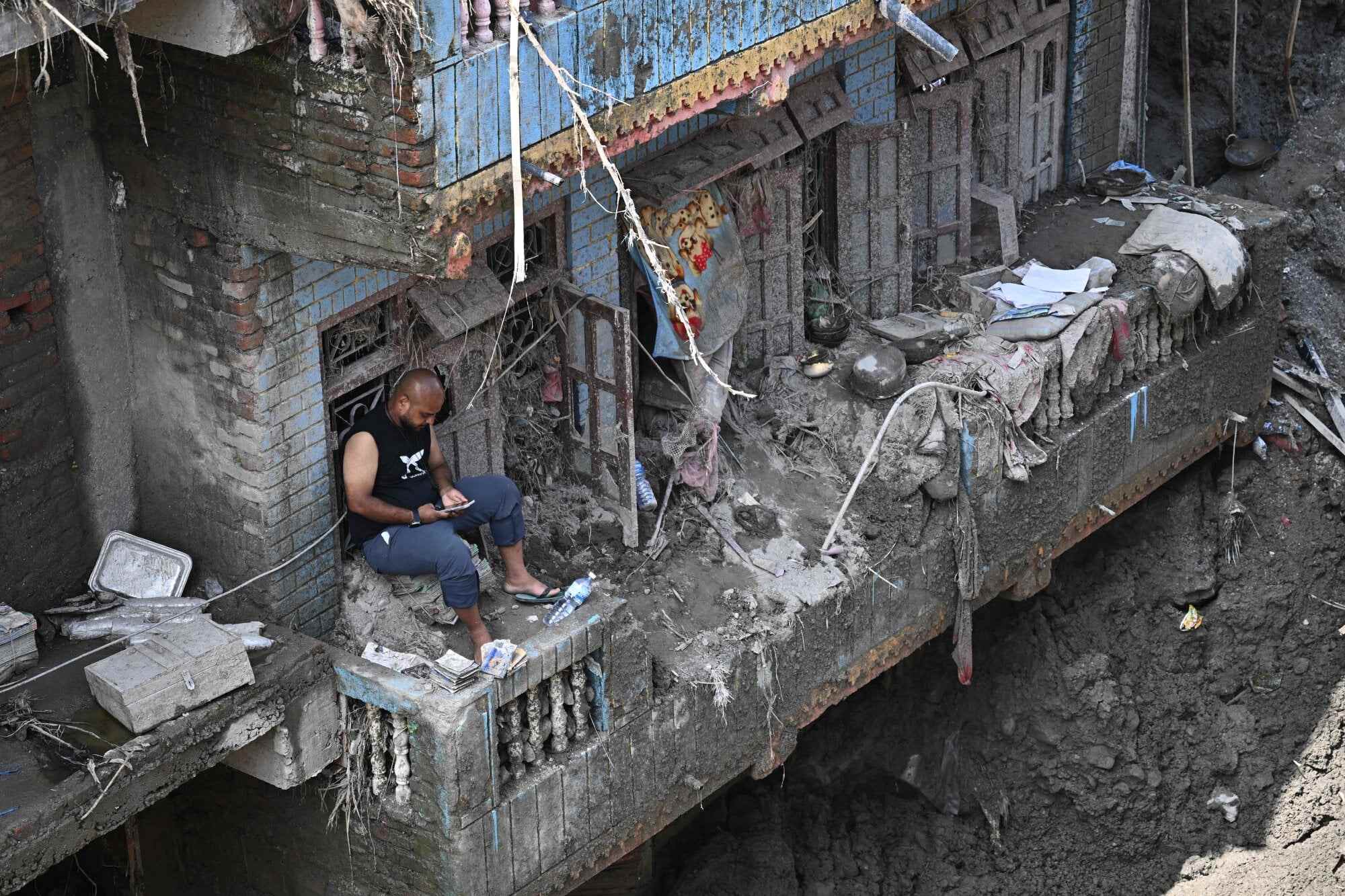 A man sits on the balcony of a sludge-ridden house in the aftermath of the flash floods at Devighat in Nepal’s Nuwakot district on September 8, 2026. Photo: AFP